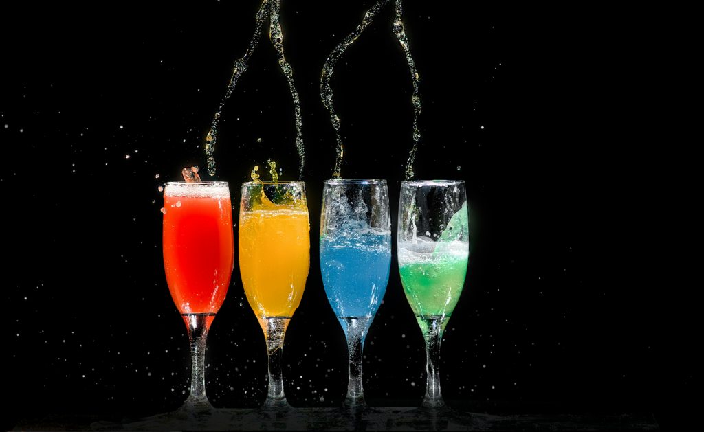 pexels-photo-1028637-1028637 Vibrant colored cocktails splashing in glasses against a black background.